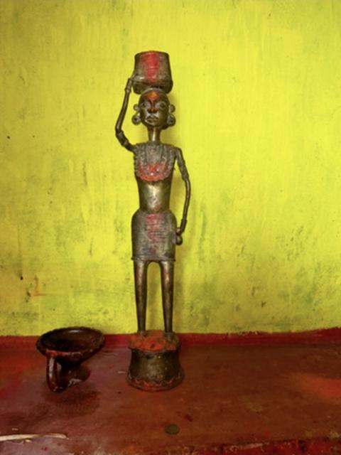 Traditional metal figurine of a woman carrying a pot
