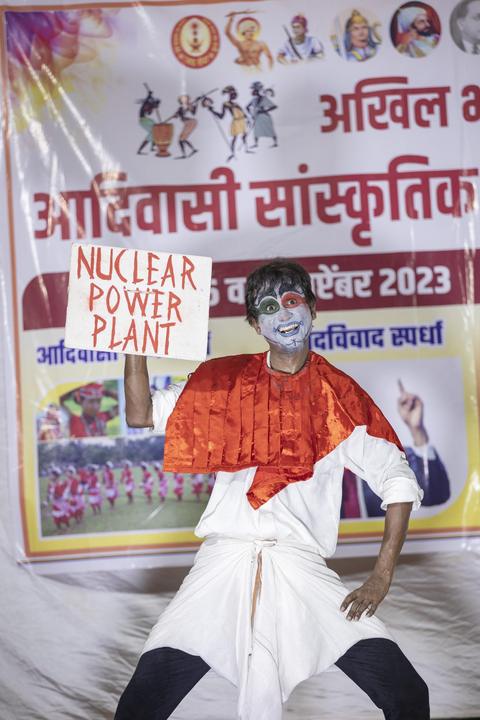 Performer in face paint holding a 'Nuclear Power Plant' placard