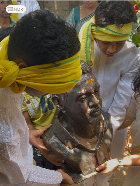 पिवळे फेटे बांधलेले कुटुंबीय कांस्य अर्धपुतळा वाहून नेताना