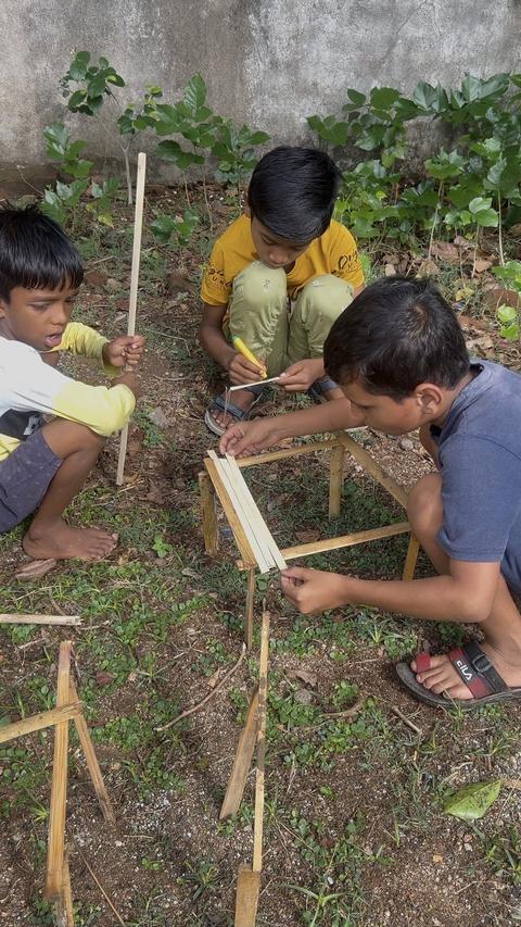 Children building bamboo stick structures outdoors