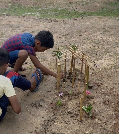 Boys building a model hut from bamboo sticks