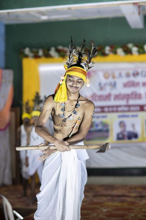Young man in feathered headdress with an axe, traditional fashion show"