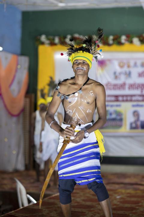Young man in feathered headdress with a sword, traditional fashion show"
