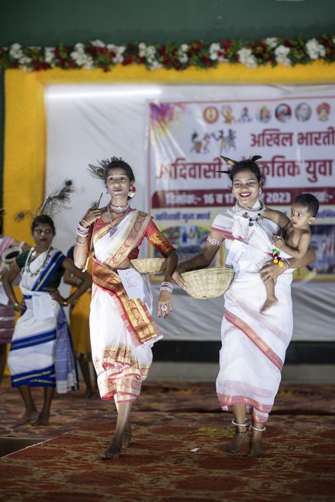 Two women in traditional dress with baskets, one carrying a child"
