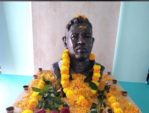 The memorial bust of Dr. Kishor Naitam, garlanded, in Alapalli